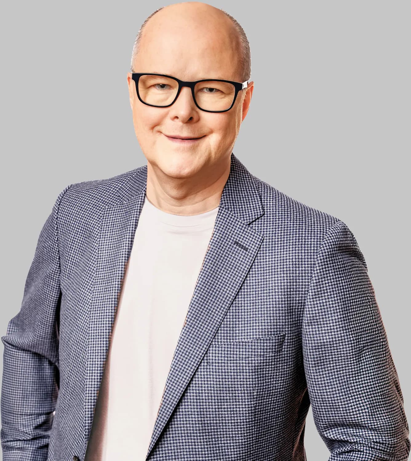 Thomas Spieker im Sakko über weißem Shirt vor hellem Studiohintergrund